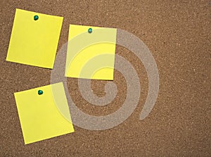 Three yellow notes papers are pinned on cork board for writing and a place for text.