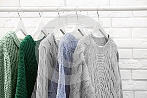 Collection of warm sweaters hanging on rack near wall