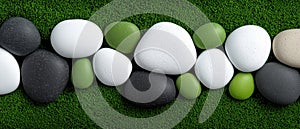 A collection of white, black, and green pebbles arranged in a row on a green surface.