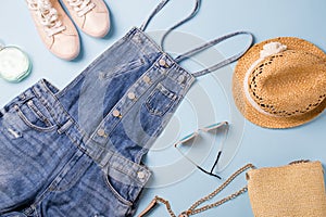 Collection of womens  summer clothes  and accessories  collage on blue. Jeans overall and wicker hat, flat lay,