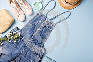 Collection of womens  summer clothes  and accessories  collage on blue. Jeans overall and wicker hat, flat lay