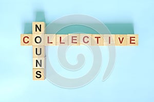 Collective nouns concept in English grammar noun education. Wooden block crossword puzzle flat lay in blue background.