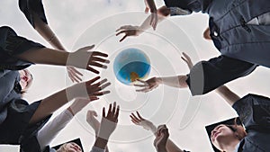 College alumni students toss a globe of the world into the sky.