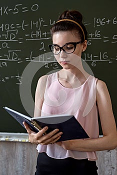 college female student writing on blackboard completing mathematical equations