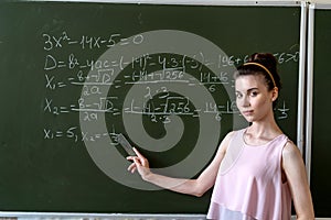 college female student writing on blackboard completing mathematical equations
