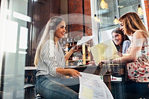 College female students sitting at table working on school assignment in a library