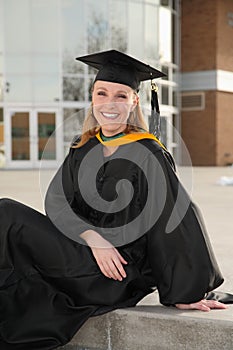 College graduate sitting in front of campus building