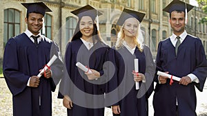 College graduates in academic regalia holding diplomas, celebrating graduation