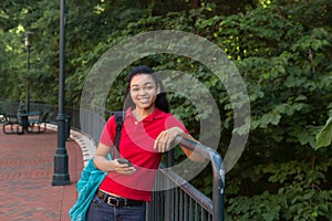 College student with a backpack looking at her cell phone