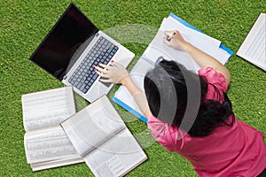 College student lying on grass while studying