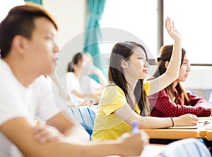 college student raise hand for question in classroom photo