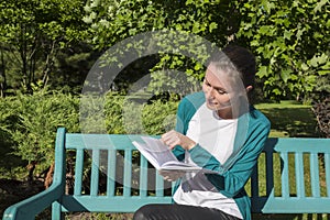 A college student reading a book on a park bench on a sunny day