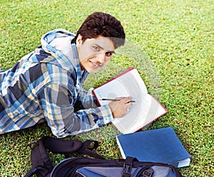 College student reading over grass.