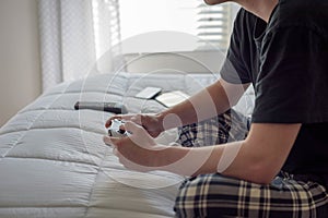 College student sitting on bed playing video games