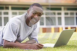 College student using laptop on campus lawn