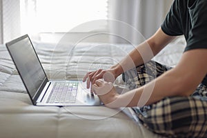 College student working on laptop on bed