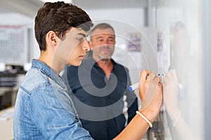 College student writing on whiteboard in classroom