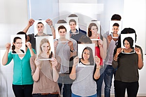 College students holding photographs in front of faces