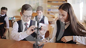 College students in school uniform working microscope sitting in the classroom. The concept of school education.