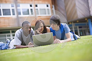 College students using laptop on campus lawn