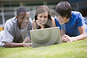 College students using laptop on campus lawn