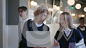 College students using laptop standing in campus corridor