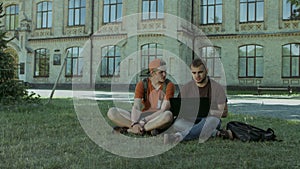 College students working on laptop on campus lawn