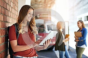 College wifi lets her study anywhere. a smiling female university student standing on campus using a digital tablet with