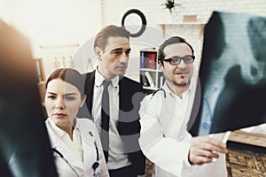 Collegium of doctors shows x-rays of bones to businessman who is being treated. Pelvic bones x-ray.