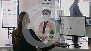 Collegues with protection medical face masks sitting at desk