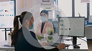 Collegues with protection medical face masks sitting at desk