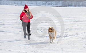 The Collie dog running with girl at winter landscape