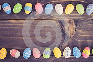 Coloeful easter eggs on plank wooden background with space.