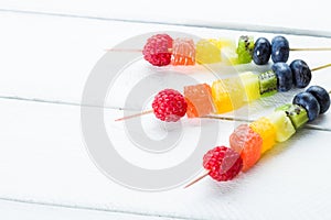 Coloerd fruits and berries kebab on wooden table