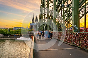 COLOGNE, GERMANY, AUGUST 11, 2018: People are passing on Hohenzollern bridge over Rhein during sunset, Germany