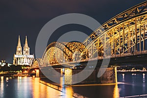 Cologne, Germany. Night View Of Cologne Cathedral And Hohenzollern Bridge. Gothic Cathedral In Dusk, Evening. UNESCO