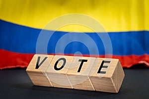 Colombia vote, the word Vote on wooden blocks against the background of the Colombian flag, the concept of voting and taking part