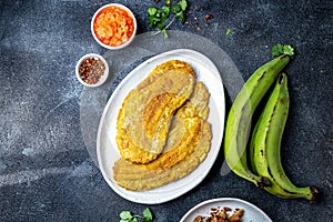 COLOMBIAN CARIBBEAN CENTRAL AMERICAN FOOD. Patacon or toston, fried and flattened whole green plantain banana on white