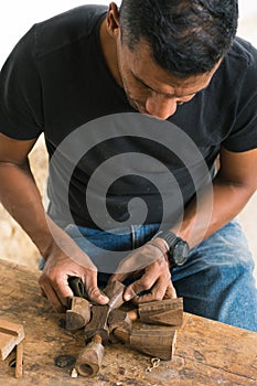 Colombian man in his workshop making wood crafts. carpenter using his tools to make pieces of wood.