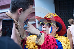 Colombian sport fan drawing russian flag on the cheek of the caucasian man sport fan at the street