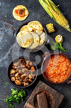 COLOMBIAN traditional food. Chicharron, maize arepas with tomato and onion sauce. Top view photo