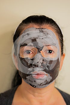 Colombian woman cleans the skin of her face with a black clay facial mask