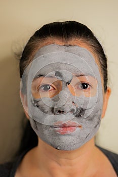 Colombian woman cleans the skin of her face with a black clay facial mask