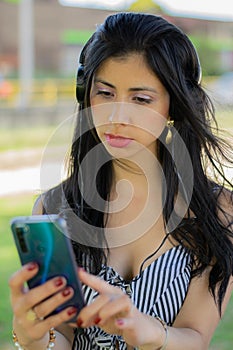 Colombian woman listens to music from her cell phone with headphones