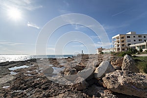 Colonia de Sant Jordi harbor, rocky cove and lighthouse on the horizon