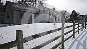 Colonial-style house exterior with wooden  post and rail fence in winter