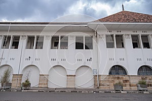 A colonial-style white building with arched windows and pillars stands under a cloudy sky photo
