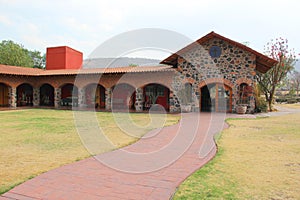 Colonnial farm and country house, stone and red brick construction with arches and green grass garden photo