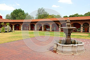 Colonnial farm and country house, stone and red brick construction with arches and green grass garden