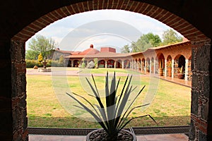 Colonnial farm and country house, stone and red brick construction with arches and green grass garden photo